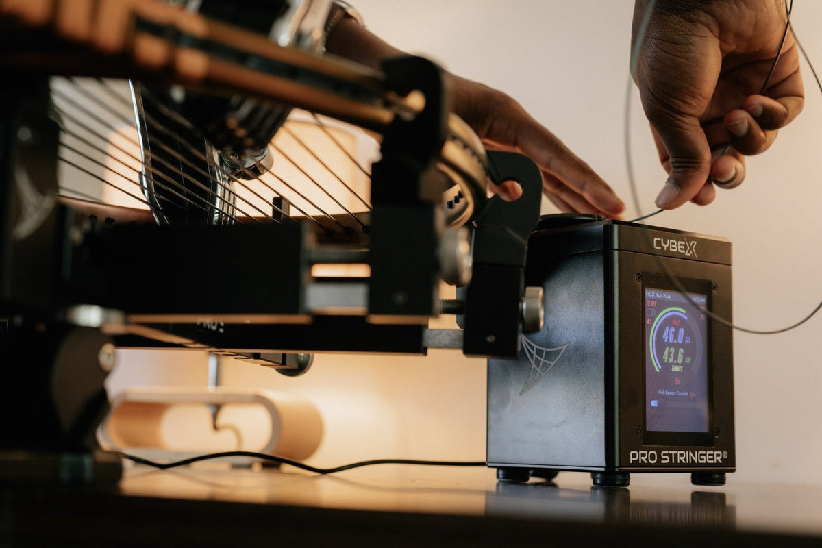Using a Pro Stringer digital tennis machine to pull tension on a racquet string during the stringing process.
