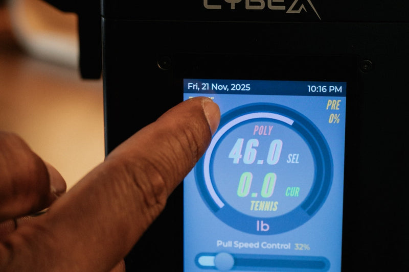 A finger adjusting the touchscreen display panel on a Pro Stringer digital tennis stringing machine.